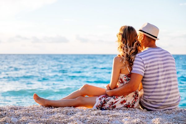 young-couple-in-love-sitting-on-the-beach-PRRSRHJ.jpg